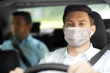 Image showing taxi driver in face protective mask driving car