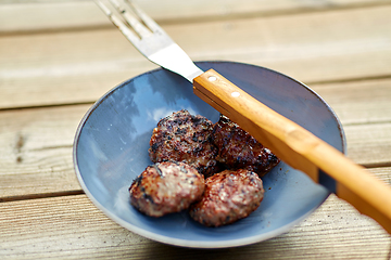 Image showing roasted meat cutlets on plate with barbeque fork