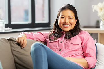 Image showing asian woman in pink shirt sitting on sofa at home