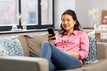 Image showing happy asian young woman with smartphone at home