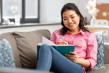 Image showing asian woman with diary sitting on sofa at home