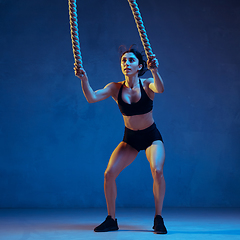 Image showing Caucasian young female athlete practicing on blue studio background in neon light