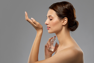 Image showing happy woman smelling perfume from her wrist