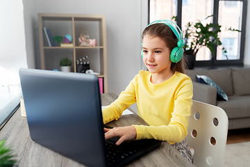 Image showing girl in headphones with laptop computer at home