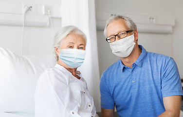 Image showing senior couple in face masks meeting at hospital