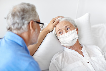 Image showing senior couple in face masks meeting at hospital