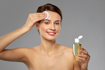 Image showing young woman with toner or cleanser and cotton pad