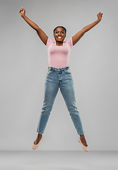 Image showing happy african american woman jumping over grey