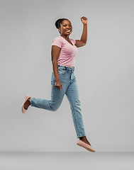 Image showing happy african american woman jumping over grey