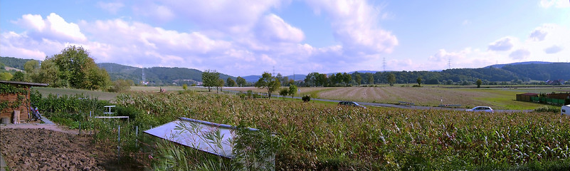 Image showing Panoramic landscape: road, cars, fields, trees, sky with clouds, horizon