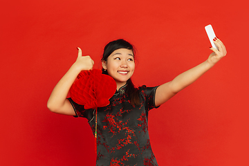 Image showing Happy Chinese new year. Asian young girls\'s portrait isolated on red background