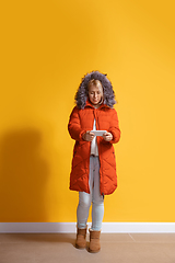 Image showing Young caucasian woman using smartphone. Full body length portrait isolated over yellow background.