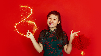 Image showing Happy Chinese New Year. Asian young girls\'s portrait isolated on red background