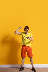 Image showing Young caucasian man using smartphone. Full body length portrait isolated over yellow background.