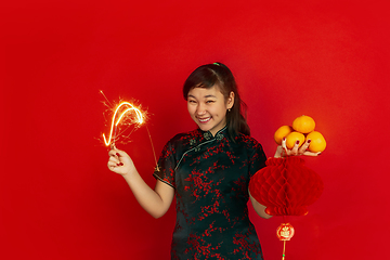 Image showing Happy Chinese New Year. Asian young girls\'s portrait isolated on red background