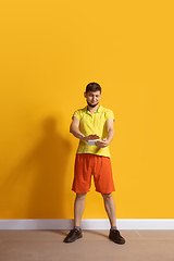 Image showing Young caucasian man using smartphone. Full body length portrait isolated over yellow background.