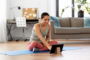 Image showing woman with tablet pc sits on exercise mat at home