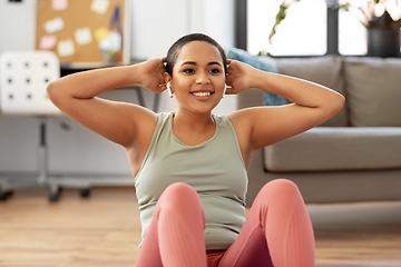 Image showing african woman doing abdominal exercises at home