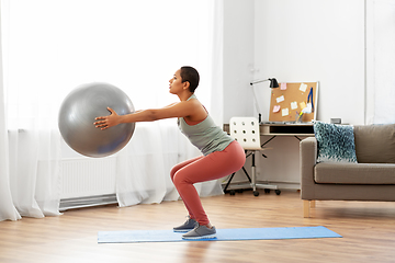 Image showing woman doing squats with fitness ball at home