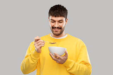 Image showing happy smiling young man eating cereals