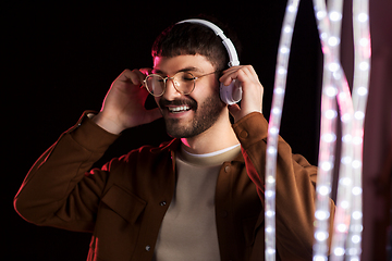 Image showing man in headphones over neon lights of night club