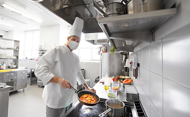 Image showing chef in mask cooking food at restaurant kitchen