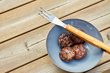 Image showing roasted meat cutlets on plate with barbeque fork