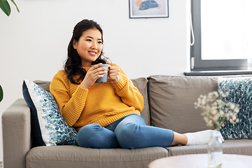 Image showing smiling asian young woman drinking coffee at home