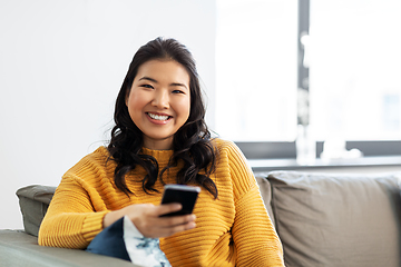 Image showing happy asian young woman with smartphone at home