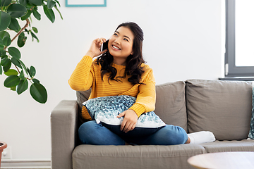 Image showing smiling asian woman calling on smartphone at home