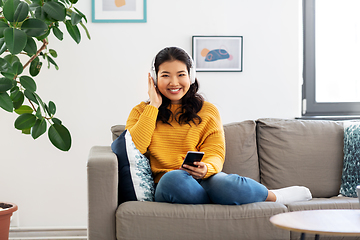 Image showing asian woman with headphones and smartphone at home