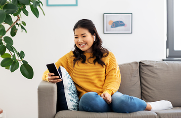 Image showing asian woman with earphones and smartphone at home