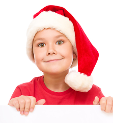 Image showing Little girl in santa hat is holding blank board