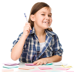 Image showing Girl is writing on color stickers using pen