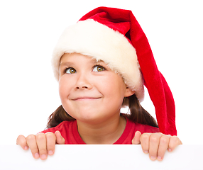 Image showing Little girl in santa hat is holding blank board