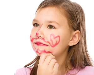 Image showing Little girl is applying lipstick on her cheek