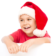 Image showing Little girl in santa hat is holding blank board