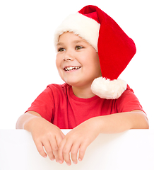 Image showing Little girl in santa hat is holding blank board