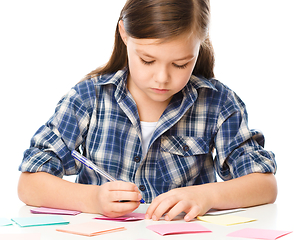 Image showing Girl is writing on color stickers using pen