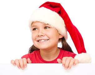 Image showing Little girl in santa hat is holding blank board