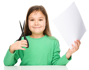 Image showing Little girl is cutting paper using scissors