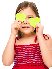 Image showing Little girl is holding hearts over her eyes