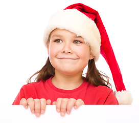 Image showing Little girl in santa hat is holding blank board