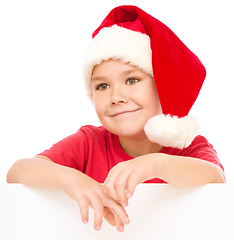 Image showing Little girl in santa hat is holding blank board