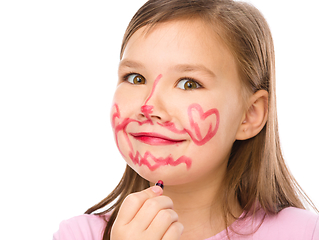 Image showing Little girl is applying lipstick on her cheek