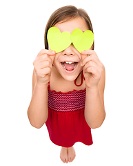 Image showing Little girl is holding hearts over her eyes