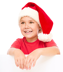 Image showing Little girl in santa hat is holding blank board