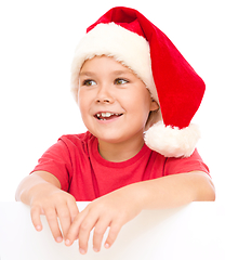 Image showing Little girl in santa hat is holding blank board