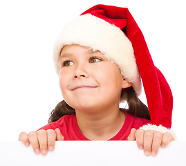 Image showing Little girl in santa hat is holding blank board