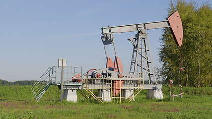 Image showing Operating oil and gas well in oil field, profiled against the blue sky